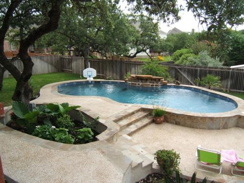 swimming pool with a small basketball goal and stone work